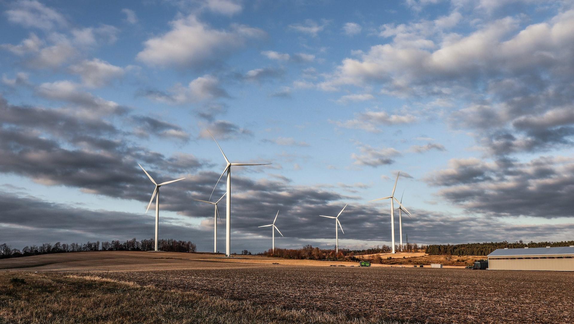 white wind turbines on brown grass field under white clouds and blue sky during daytime